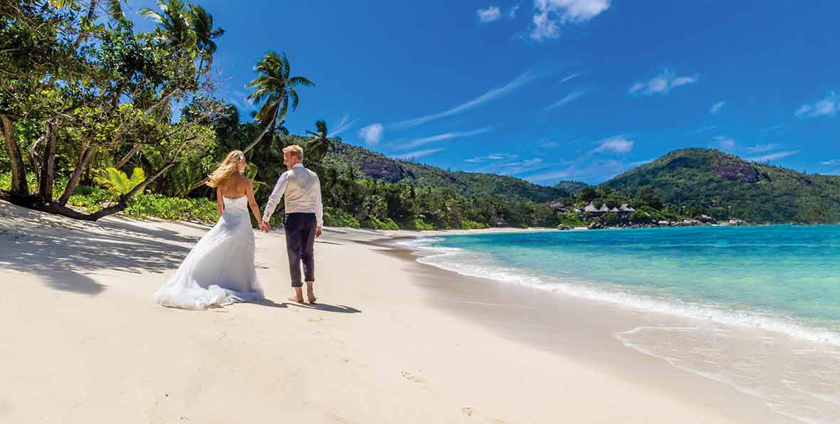 pareja en la playa de Kempinski Seychelles