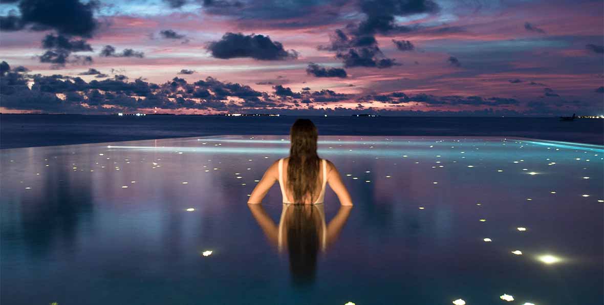 modelo en la infinity pool de noche en fushifaru maldives